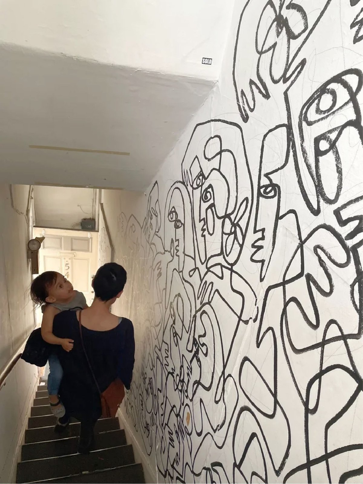 A line drawing running along a white stairwell wall.