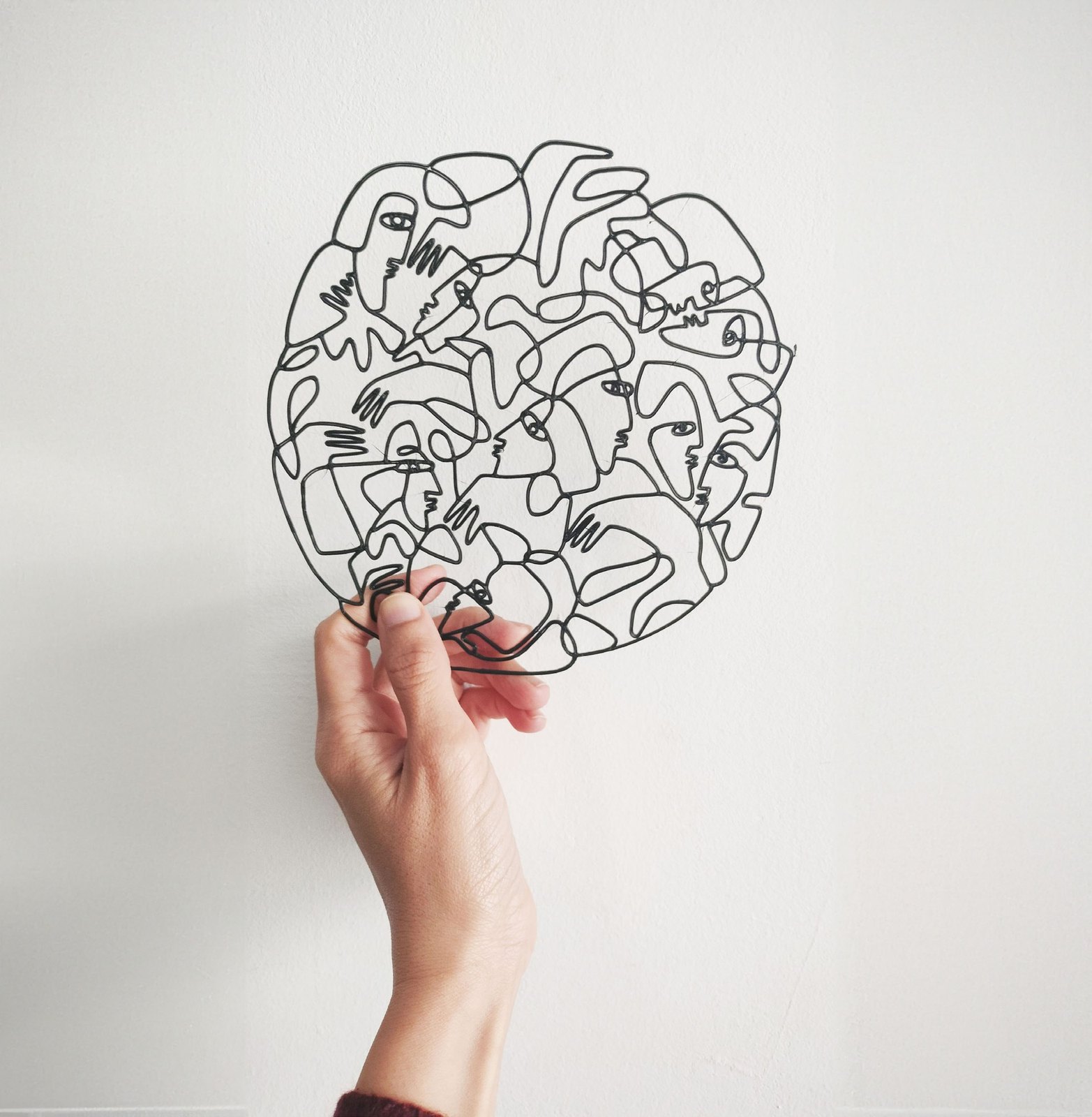 A round 3D printed drawing held against a white wall.