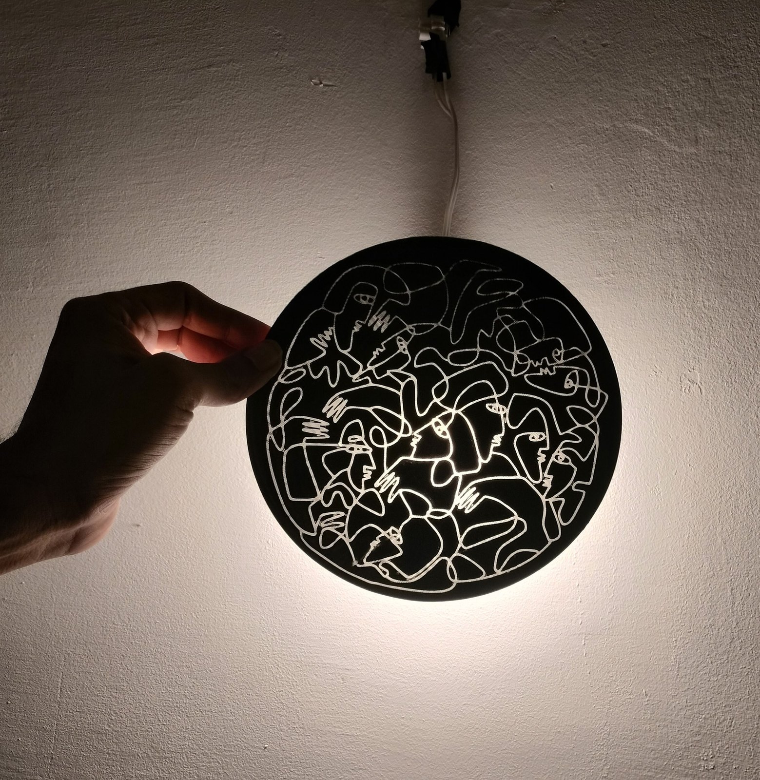 A round 3D printed drawing lit from behind, casting shadow.