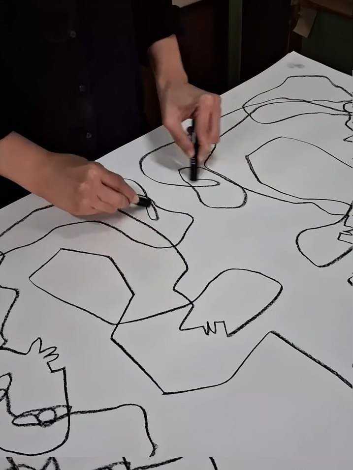 Drawing a line on a large sheet on the floor.