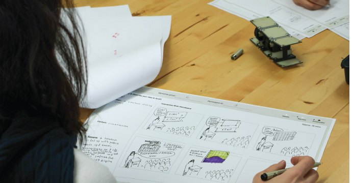 A participant colouring a storyboard, with the toy model on the table.