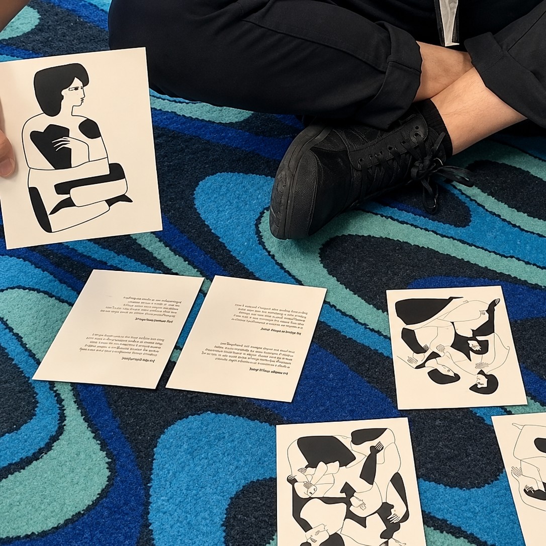 A visitor sitting on the carpet holding one card, with other cards laid out in front.