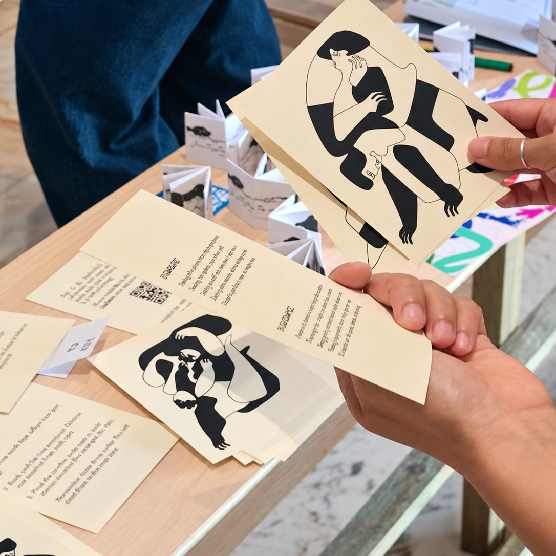 A visitor holding a card and its description at a table of printed cards.