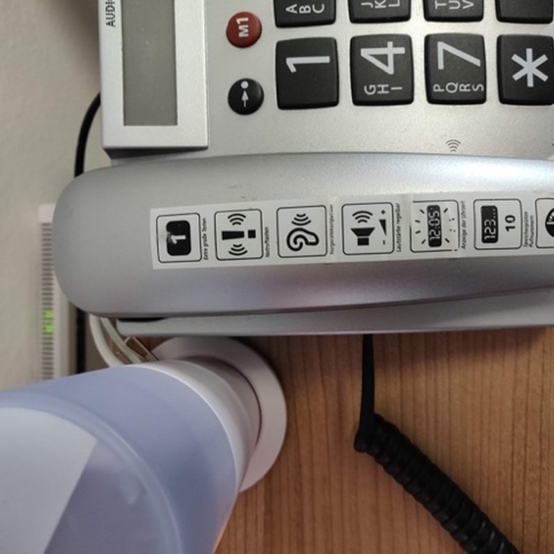 A desk phone with large number keys and picture buttons.