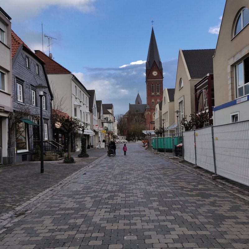 A cobbled street in the old town of Arnsberg, with a church spire.