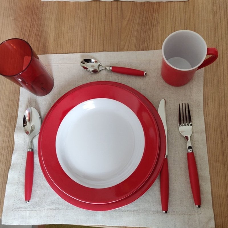 A place setting with red-rimmed plate, red cup and red-handled cutlery.