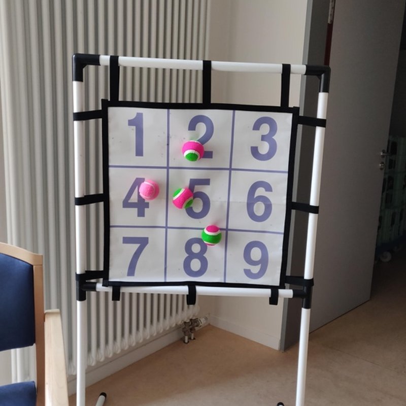 A grid of numbers with balls stuck to it, used for a counting game.